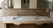 Contemporary double sink unit complimented by tavertine tiles.